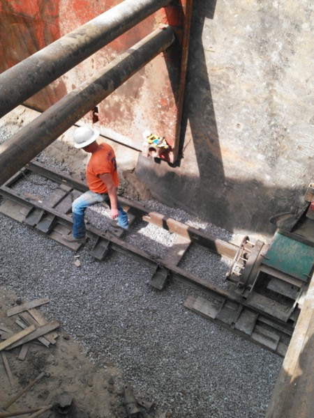 Crew member grading stone inside a shored trench
