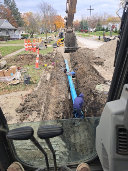 Blue utility line being installed through a residential yard